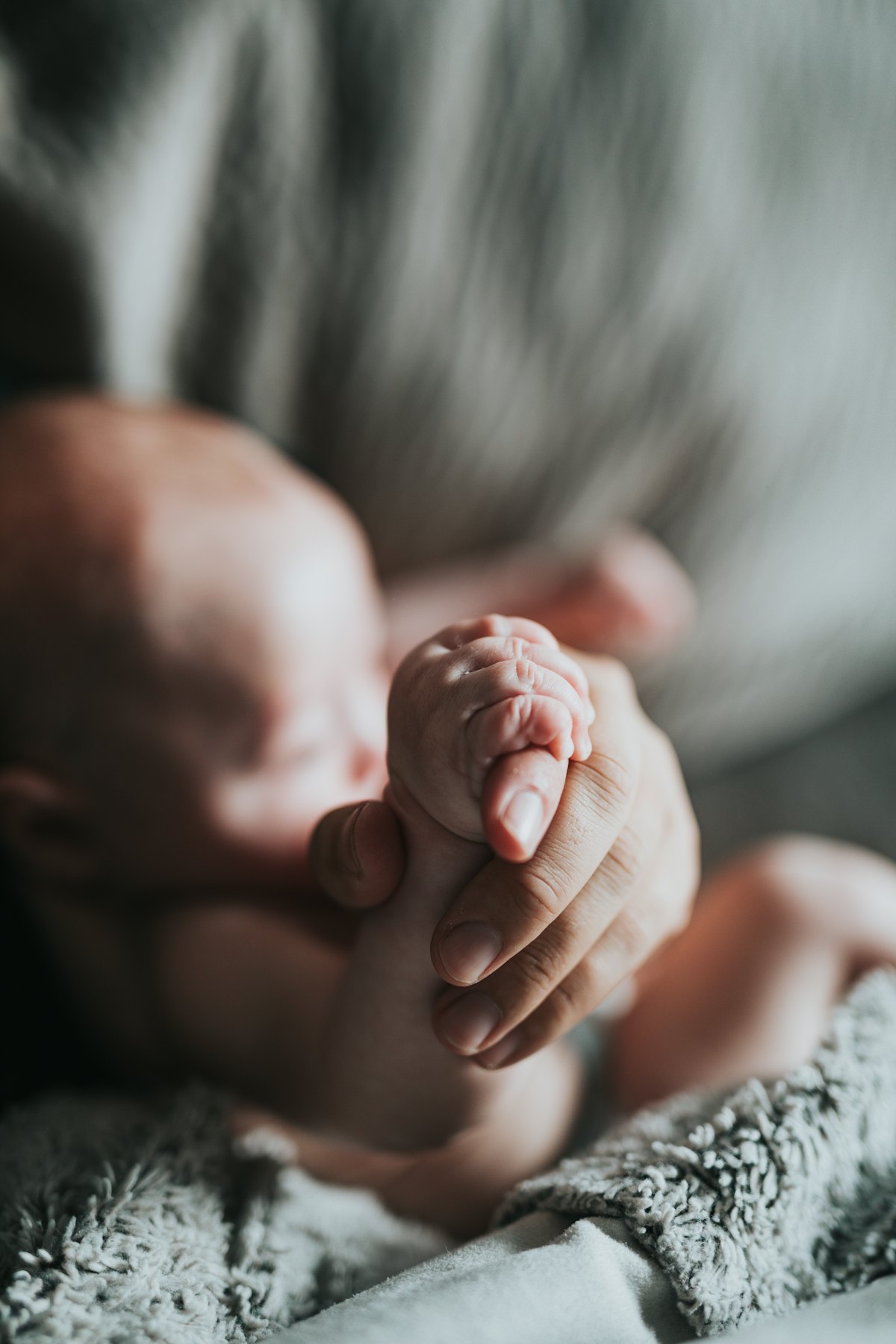 Accompagner la dépression post-partum Main d'un parent tenant celle de son nouveau-né, symbole du lien retrouvé grâce au traitement de la dépression post-partum