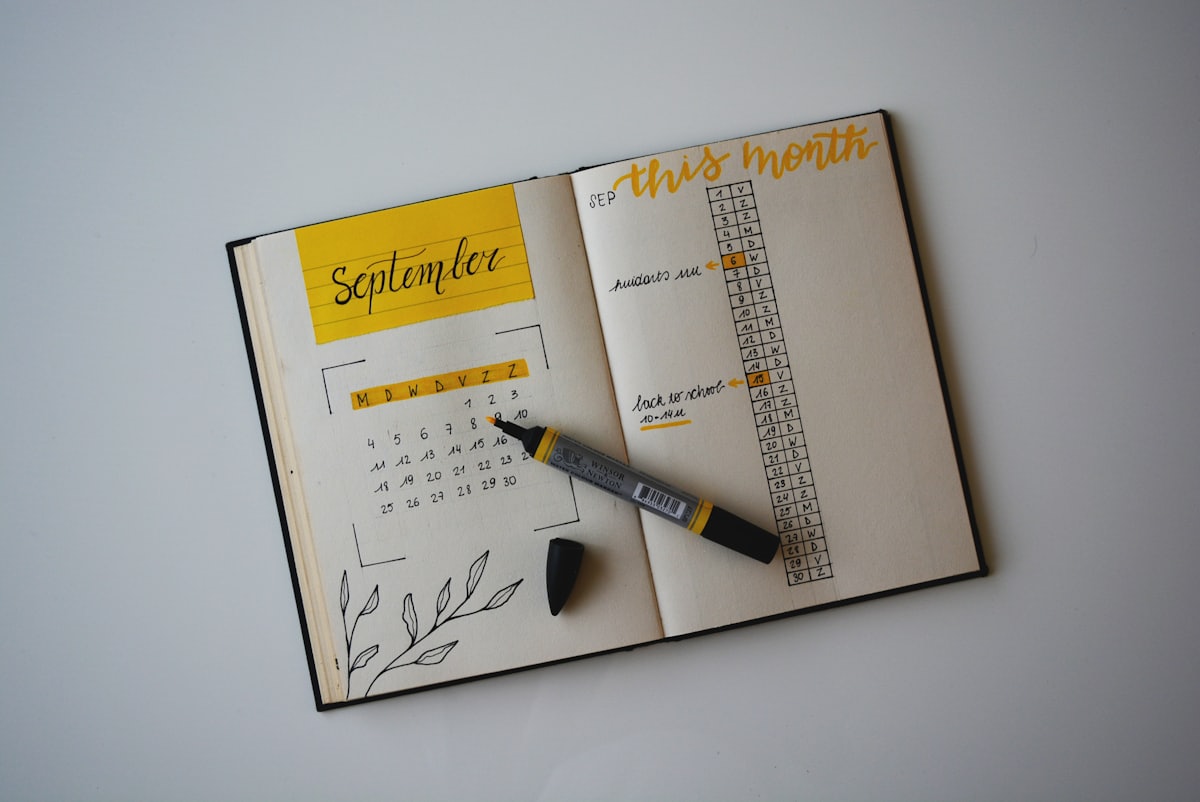 Carnet de suivi de l'humeur et agenda Carnet de suivi de l'humeur ouvert avec agenda mensuel et stylo, illustrant la régularité du quotidien dans le traitement du trouble bipolaire