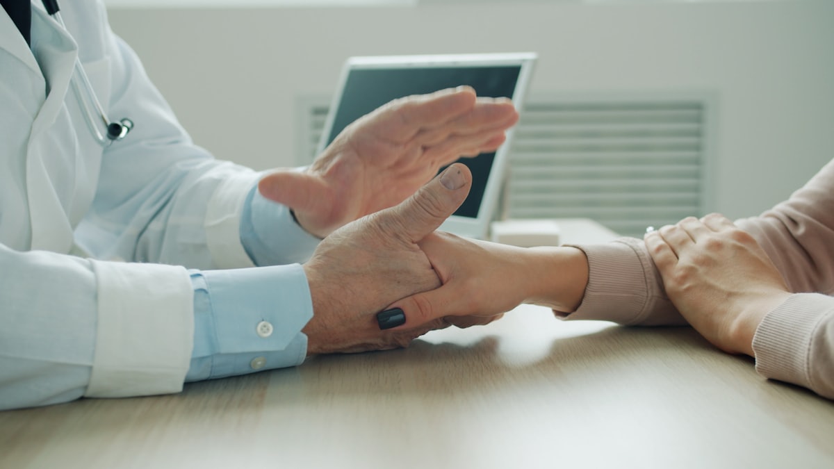 Médecin tenant la main d'une patiente en consultation, geste de soutien face aux signes de dépression