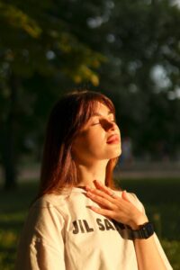 Femme pratiquant la respiration profonde en extérieur, main sur la poitrine, pour calmer une crise d'angoisse
