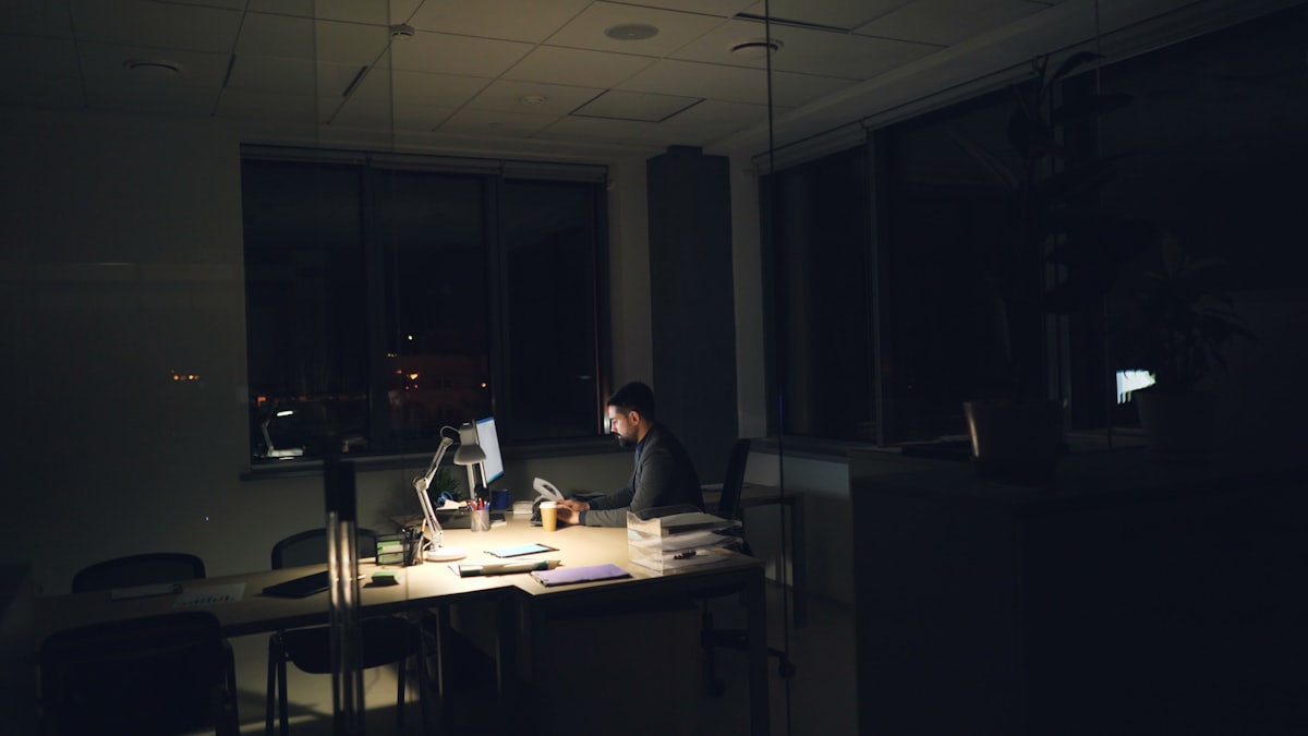 Employé travaillant tard le soir dans un bureau sombre, illustrant les symptômes d'épuisement professionnel du burn-out