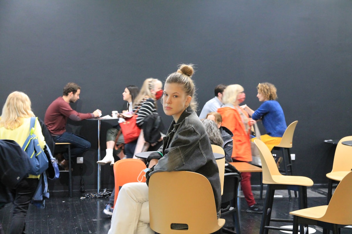 Symptômes de la phobie sociale Jeune femme assise seule, en retrait des groupes qui discutent, illustrant l'isolement social lié à la phobie sociale