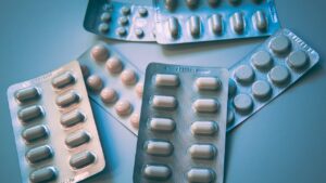 Plaquettes de comprimés et gélules sur fond bleu sobre, illustrant un traitement antidépresseur suivi en psychiatrie