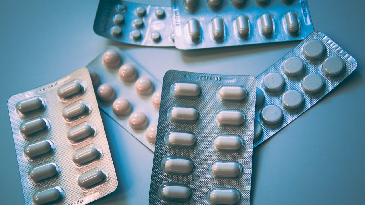 Plaquettes de comprimés et gélules sur fond bleu sobre, illustrant un traitement antidépresseur suivi en psychiatrie