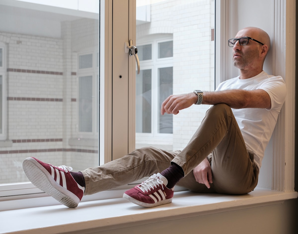 Être prêt à reprendre après un burn-out Homme assis près d'une fenêtre, moment de pause et de récupération après un burn-out avant de reprendre le travail