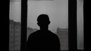 رجل شارد الذهن عند نافذته مساءً، يوضّح علامات الاكتئاب لدى الرجل — الدكتورة مينا ستلي، طبيبة نفسية في مراكش