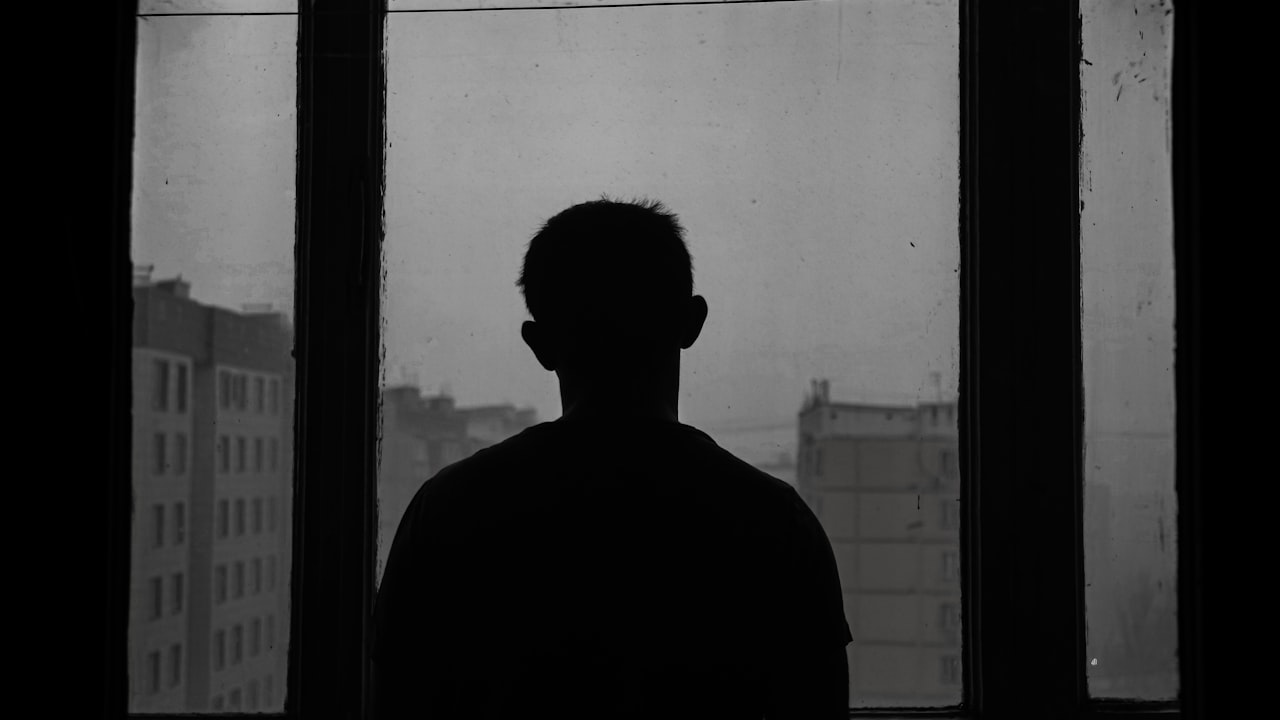 رجل شارد الذهن عند نافذته مساءً، يوضّح علامات الاكتئاب لدى الرجل — الدكتورة مينا ستلي، طبيبة نفسية في مراكش
