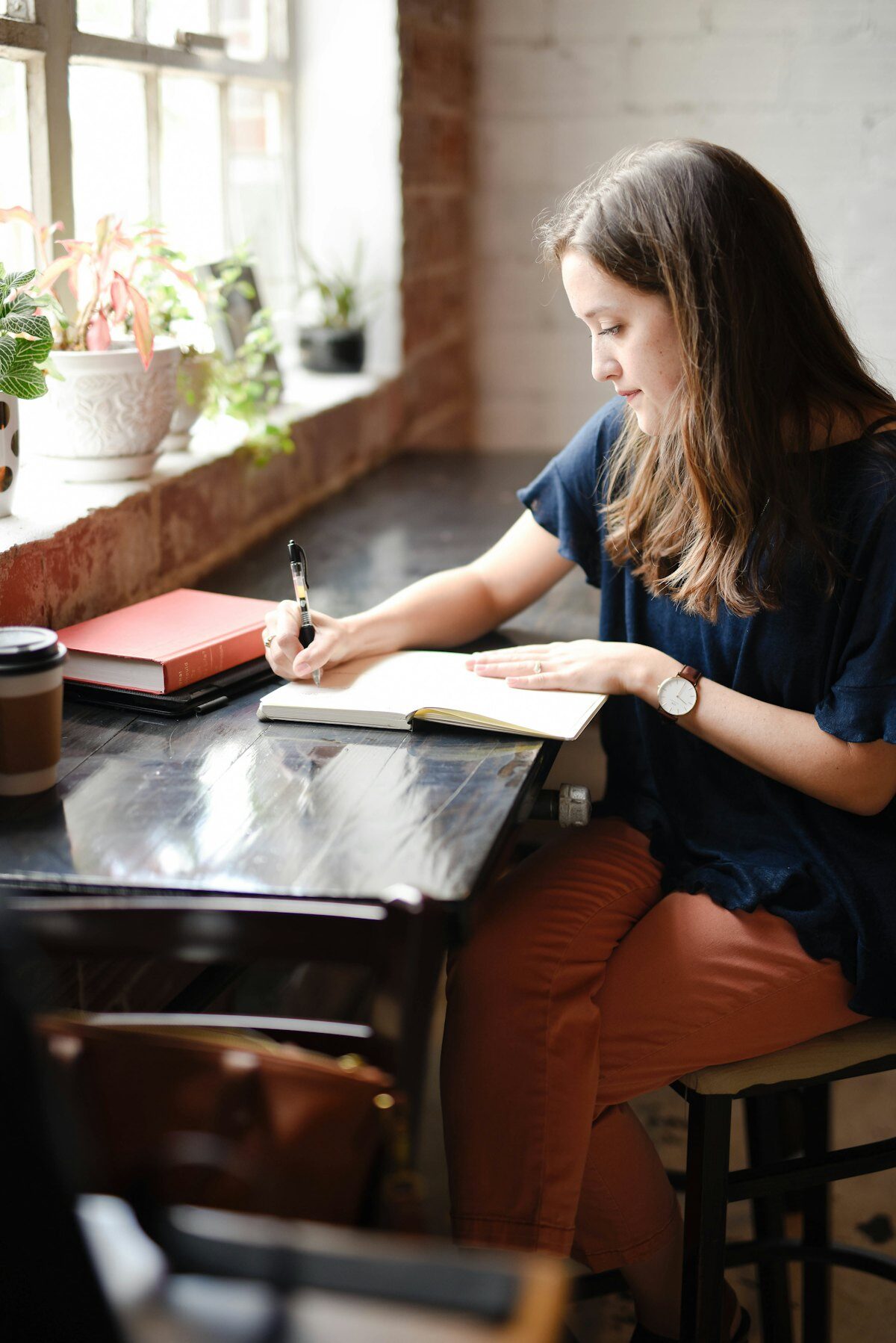 Femme écrivant dans un carnet près d'une fenêtre, symbolisant l'écriture d'un plan de prévention de la rechute dépressive