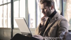 Adulte pensif la main au menton devant son ordinateur, illustrant les difficultés de concentration du TDAH chez l'adulte