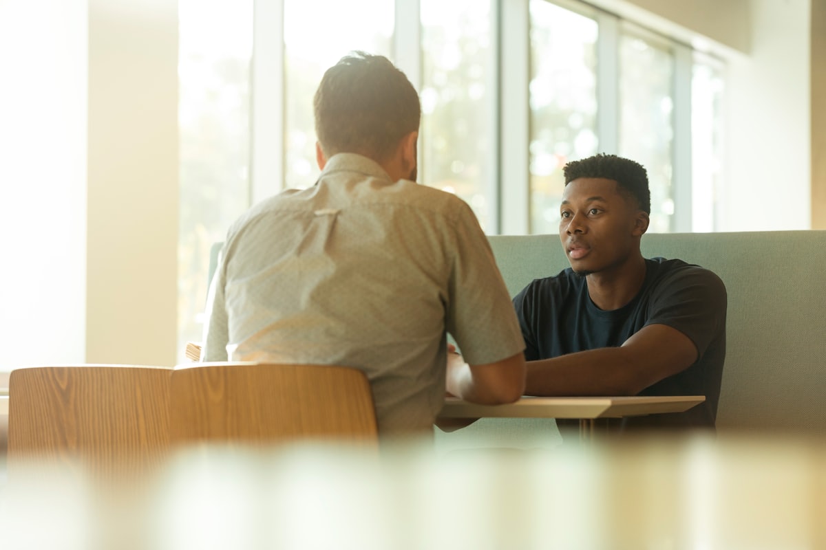 Se soigner de la dépression Deux hommes en entretien, l'un écoutant l'autre, illustrant le traitement de la dépression chez l'homme