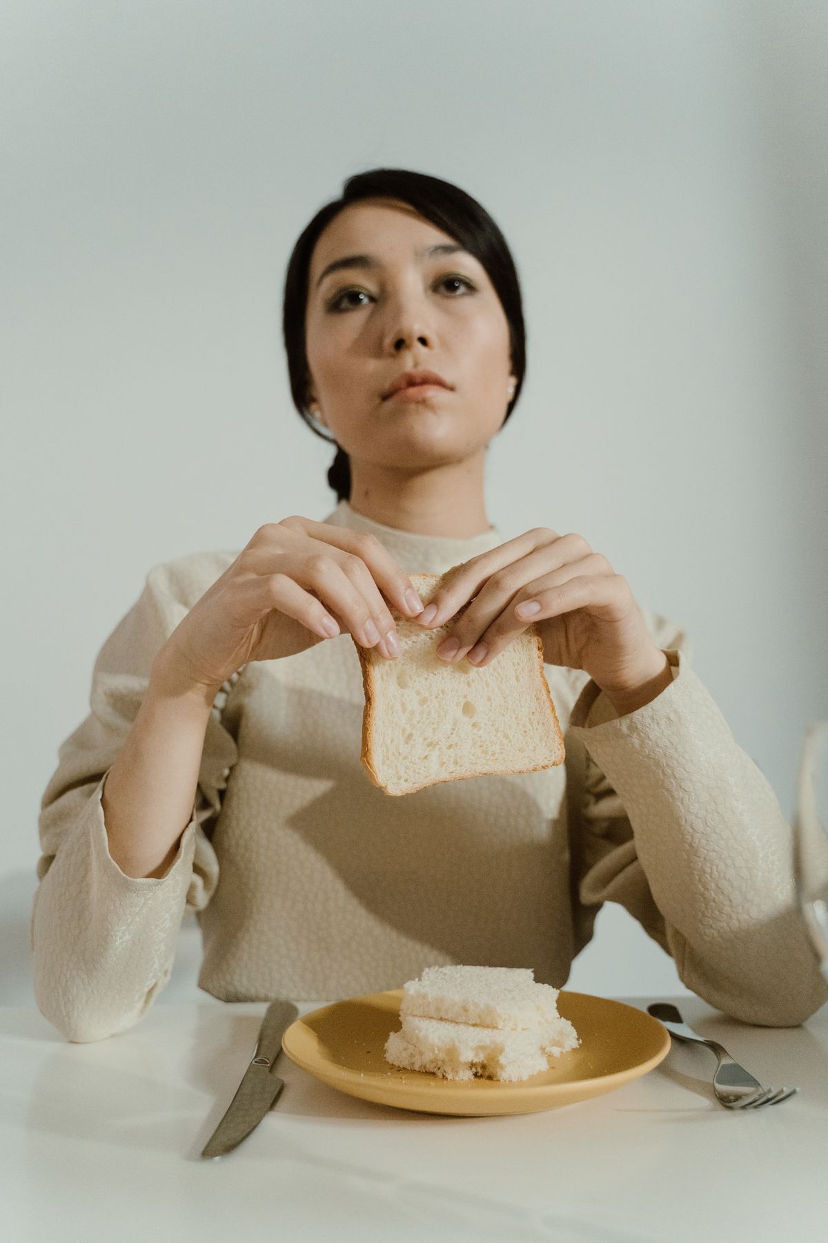 Signes des troubles alimentaires Jeune femme hésitante devant un repas, signes évocateurs de troubles alimentaires