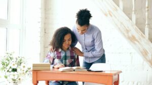 أم تضع يدها على كتف ابنتها الجالسة إلى مكتبها: دعم الوالدين في مواجهة الاكتئاب لدى المراهقين