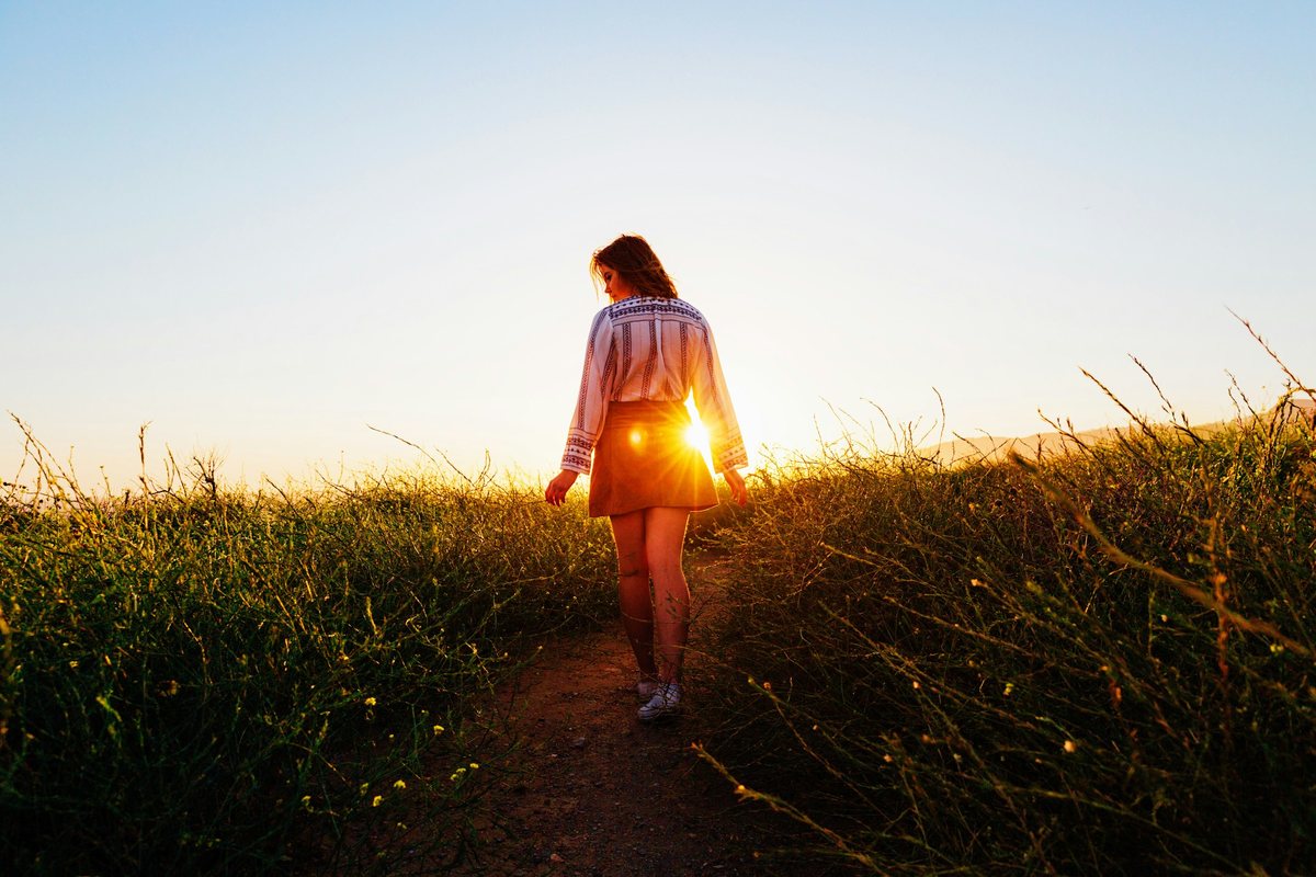 Femme qui marche lentement sur un sentier au coucher du soleil