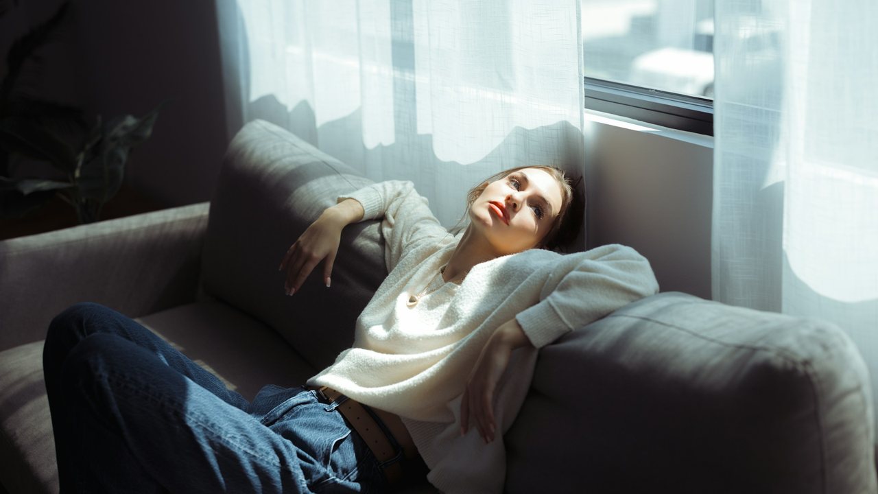 Femme épuisée allongée sur un canapé, le regard dans le vide : l'épuisement de la fatigue chronique