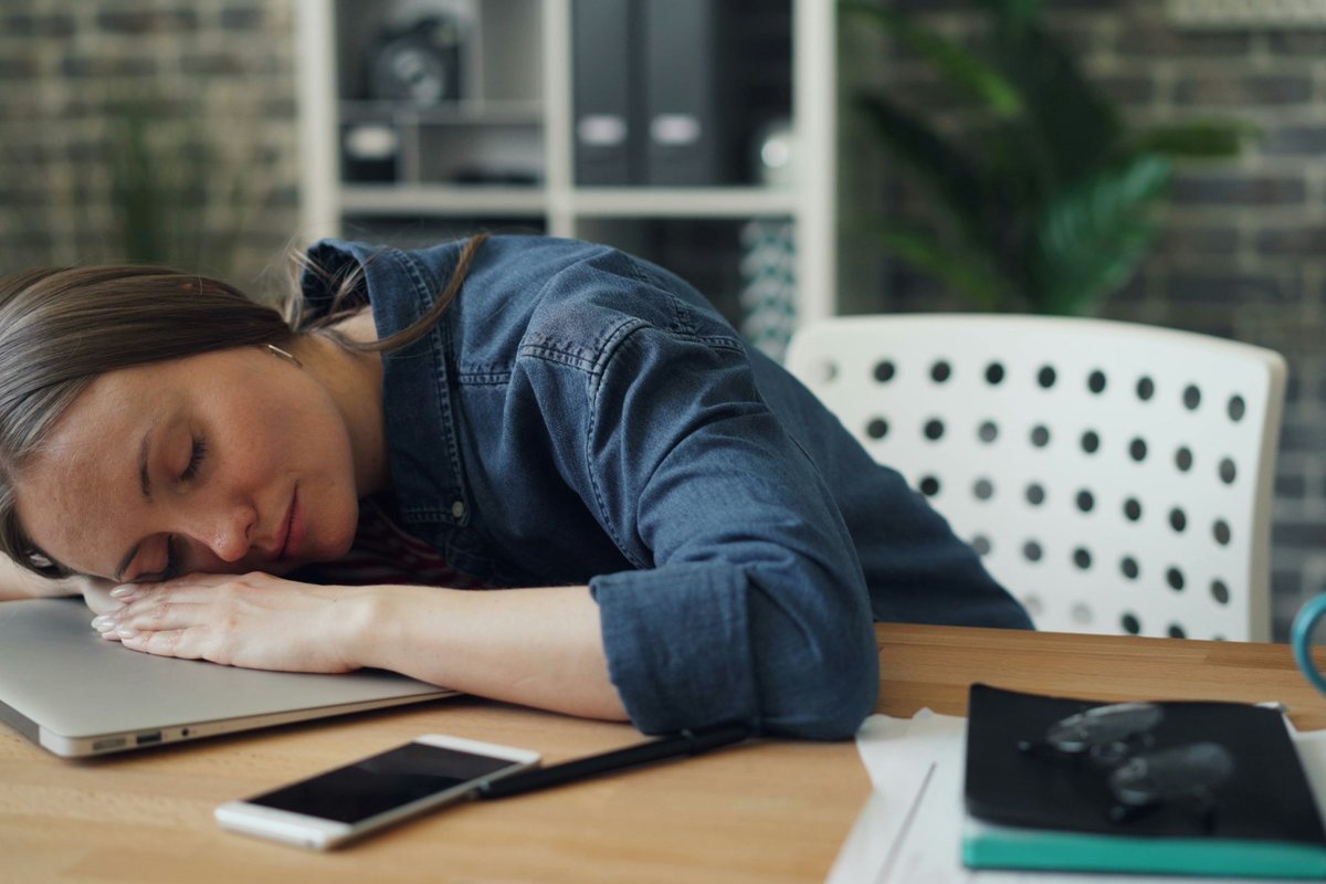 Femme endormie à son bureau, la tête posée sur son ordinateur portable