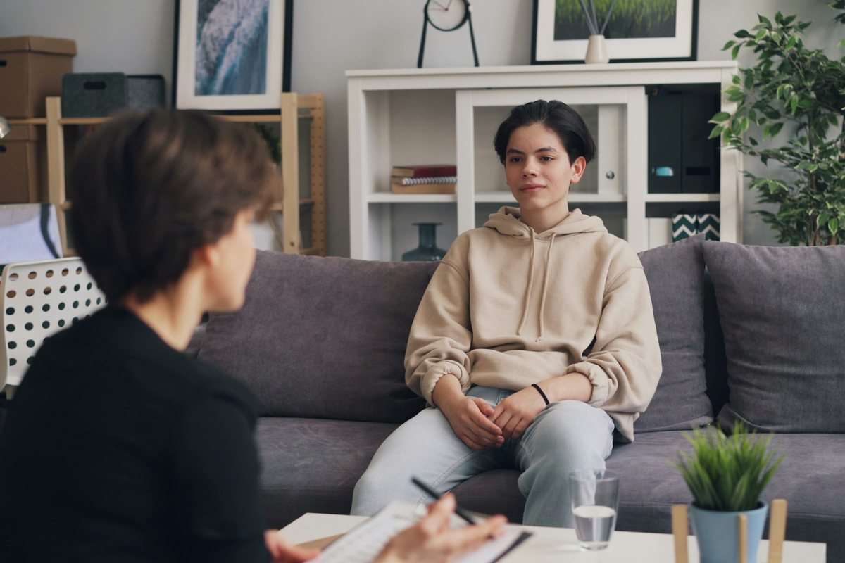 Une jeune personne assise sur un canapé échange avec une soignante qui prend des notes