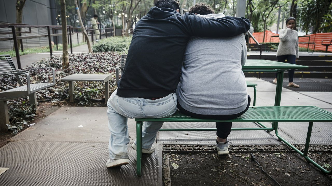 Deux personnes enlacées sur un banc de parc, vues de dos : le soutien d'un proche compte dans la prévention du suicide